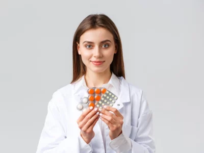Female doctor holding a few packs of pills.