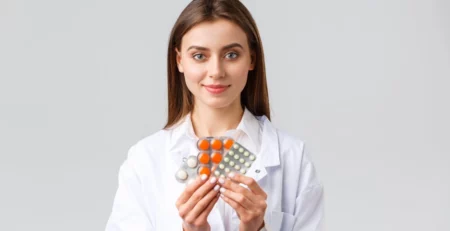 Female doctor holding a few packs of pills.