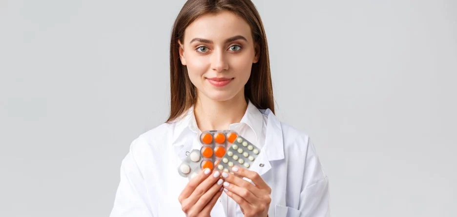 Female doctor holding a few packs of pills.