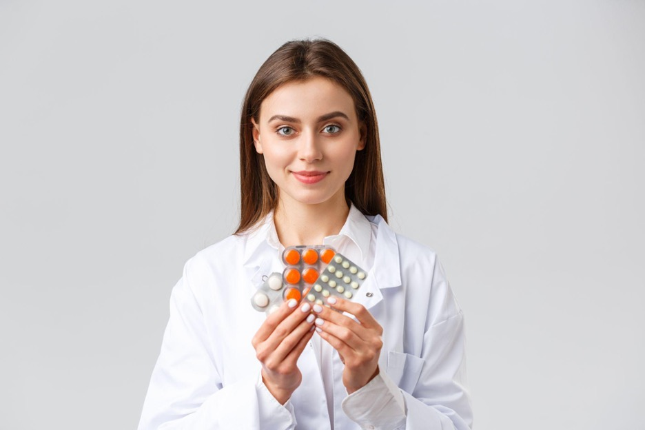 Female doctor holding a few packs of pills.
