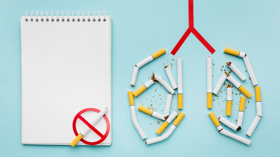Broken cigarettes forming a lung shape with no smoking symbol and a blank notebook.